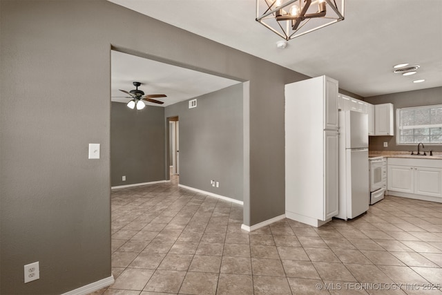 kitchen featuring light countertops, hanging light fixtures, white cabinets, a sink, and white appliances