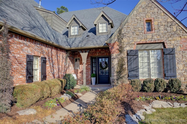 property entrance with roof with shingles, stone siding, and brick siding