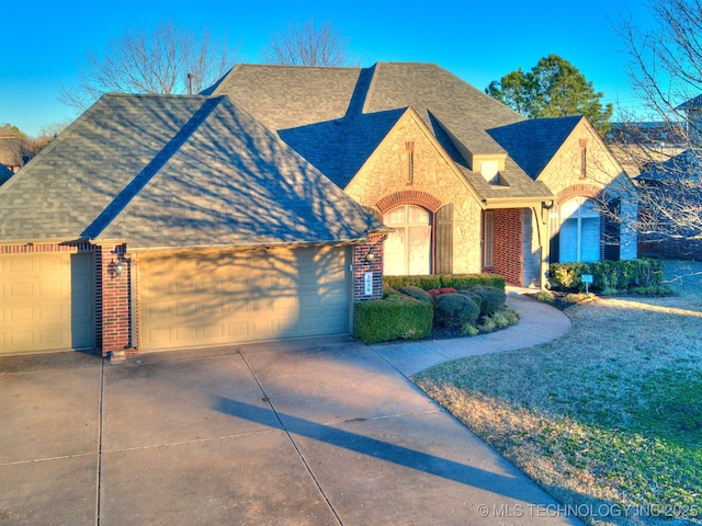 view of front of house featuring concrete driveway, a shingled roof, an attached garage, and brick siding