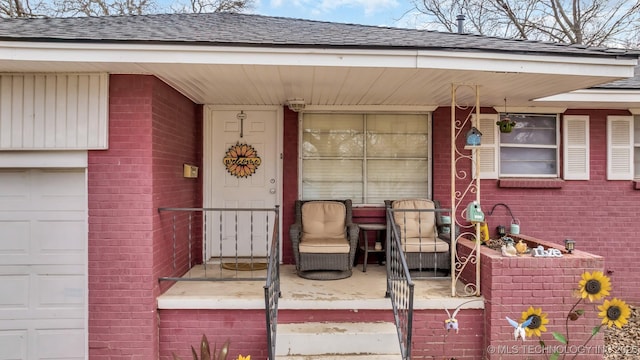 property entrance with a garage, brick siding, and a shingled roof