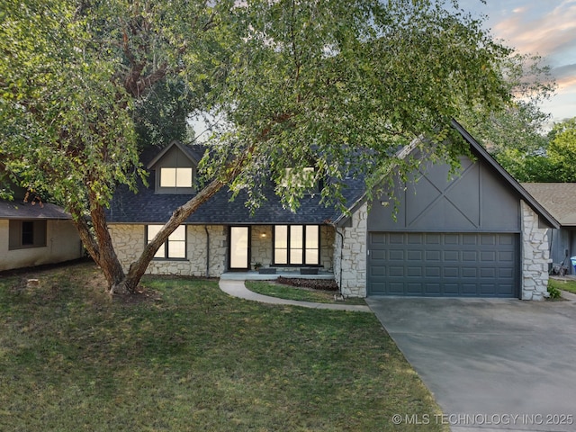 view of front facade with a garage, a yard, driveway, and roof with shingles