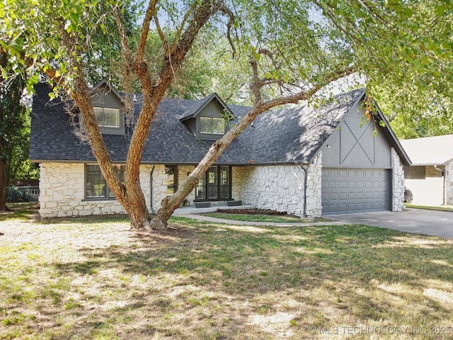 view of front facade featuring stone siding, roof with shingles, an attached garage, and driveway