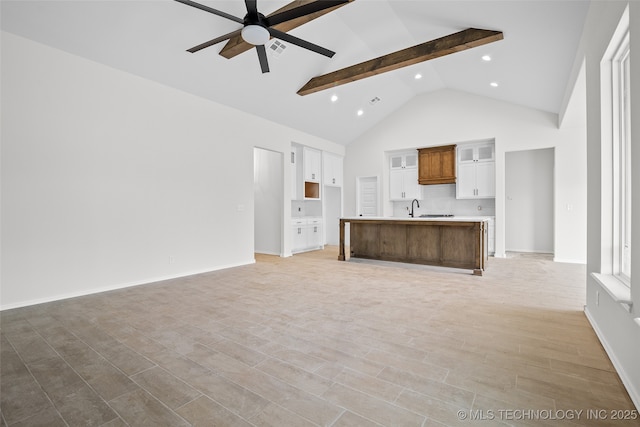 unfurnished living room with beam ceiling, light wood finished floors, a ceiling fan, a sink, and high vaulted ceiling