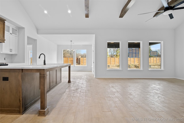 kitchen featuring glass insert cabinets, hanging light fixtures, vaulted ceiling, light countertops, and white cabinetry