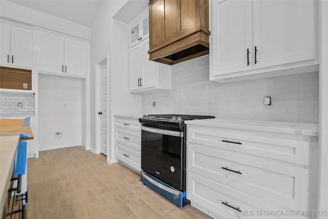 kitchen featuring stainless steel range oven, light stone counters, glass insert cabinets, and white cabinets