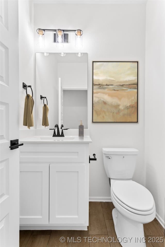 bathroom featuring baseboards, vanity, toilet, and wood finished floors