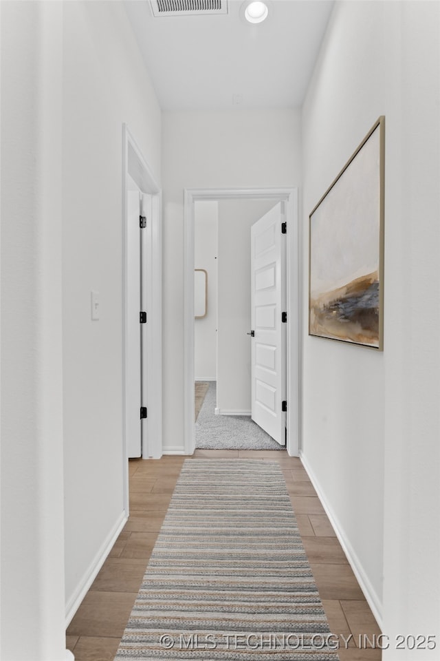 corridor featuring light wood-style flooring, visible vents, and baseboards