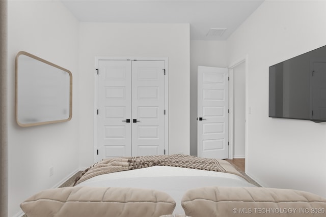 bedroom with baseboards, visible vents, and a closet