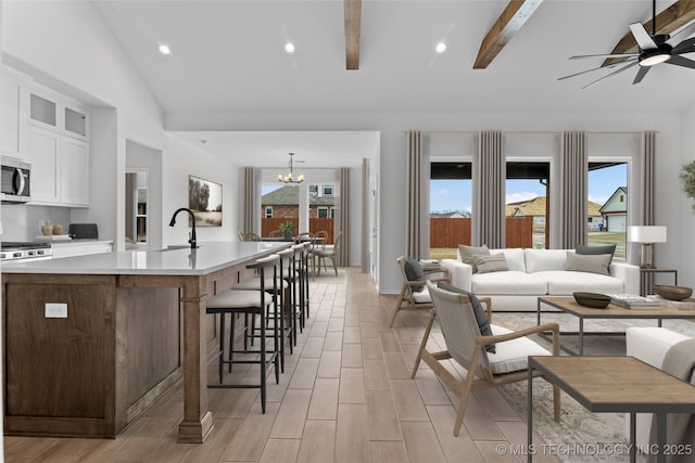 kitchen featuring white cabinets, light countertops, stainless steel microwave, glass insert cabinets, and pendant lighting