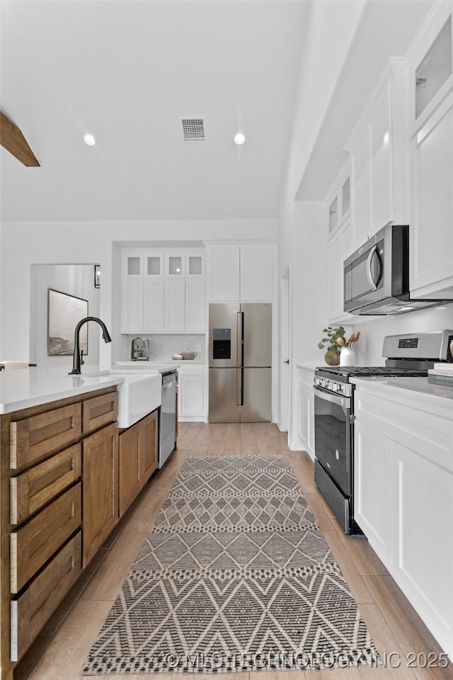 kitchen featuring glass insert cabinets, light countertops, white cabinets, and stainless steel appliances