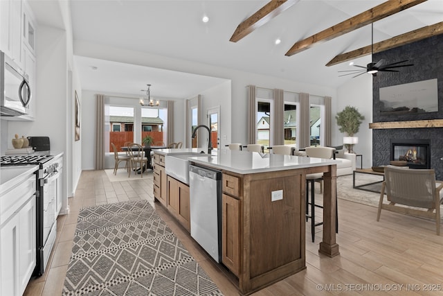 kitchen featuring stainless steel appliances, white cabinets, a sink, and an island with sink