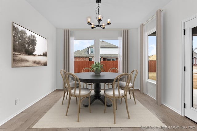 dining area featuring wood tiled floor, a notable chandelier, and baseboards