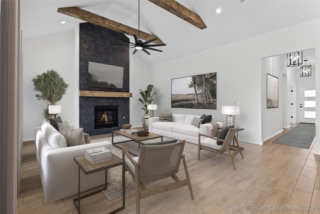 living room featuring beam ceiling, light wood-style flooring, and a premium fireplace