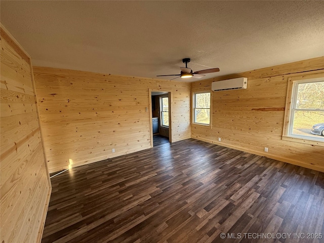 unfurnished room featuring dark wood-type flooring, plenty of natural light, a textured ceiling, and a wall mounted AC