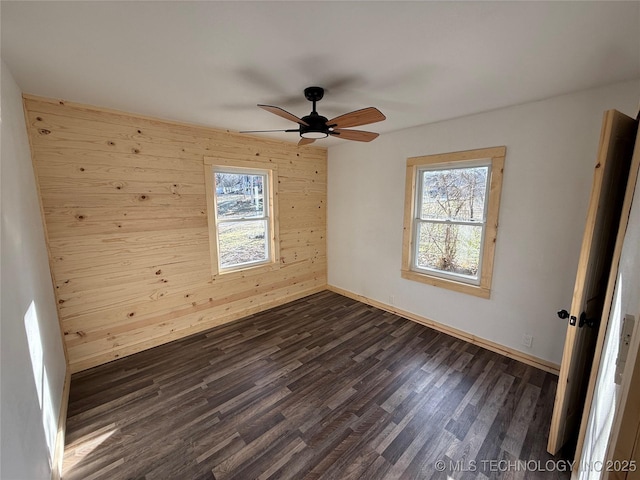 empty room with dark wood-style floors, a healthy amount of sunlight, and baseboards