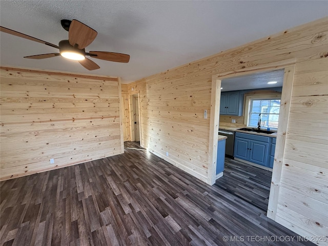 empty room featuring dark wood-style floors, a sink, and wooden walls