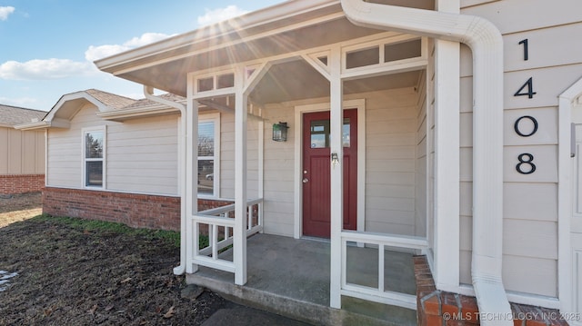 entrance to property featuring brick siding and roof with shingles