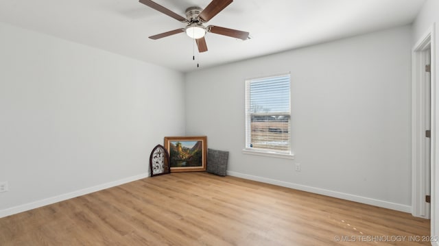 spare room featuring light wood finished floors, a ceiling fan, and baseboards