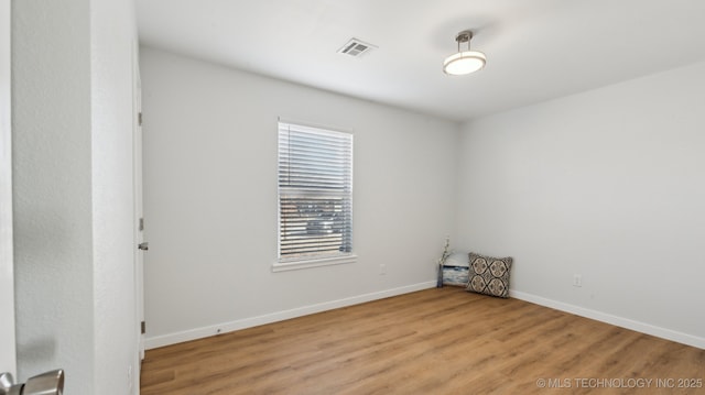 empty room featuring baseboards, visible vents, and light wood finished floors