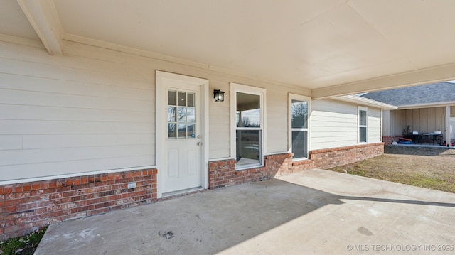 view of exterior entry with a patio area and brick siding