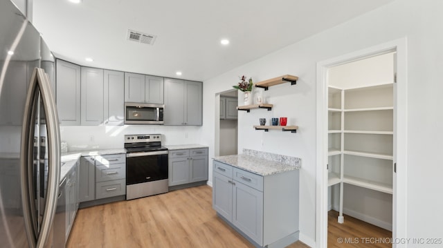 kitchen with visible vents, gray cabinets, stainless steel appliances, light wood-style floors, and open shelves