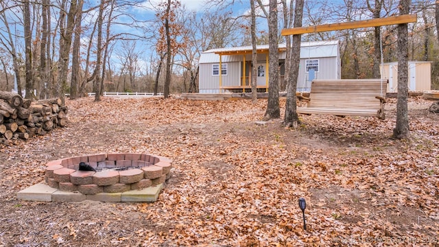 view of yard featuring an outdoor fire pit, a storage unit, and an outbuilding