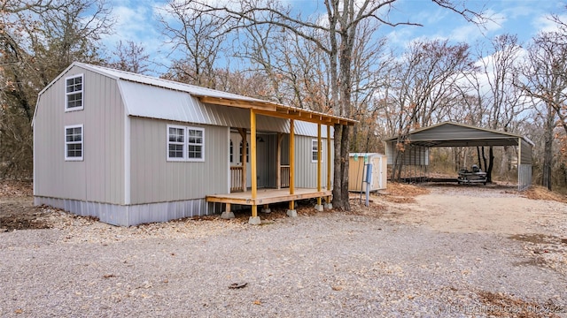 view of outdoor structure with dirt driveway and a detached carport