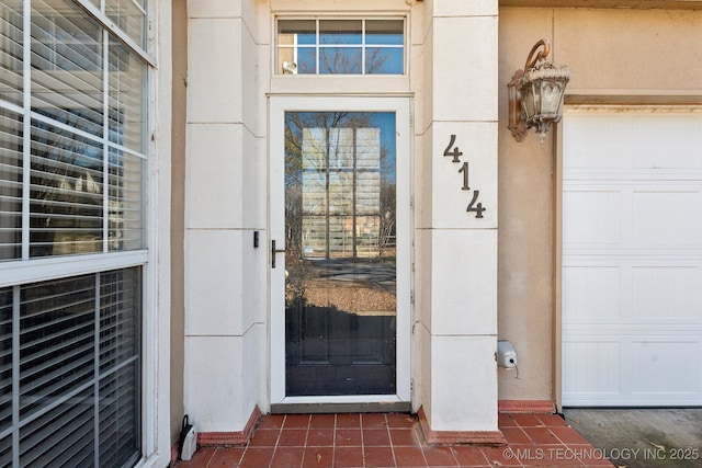 entrance to property featuring a garage and stucco siding
