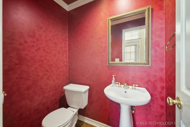 half bathroom featuring baseboards, ornamental molding, and toilet