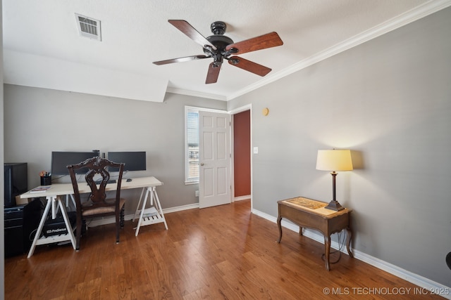 office area with wood finished floors, a ceiling fan, visible vents, baseboards, and crown molding