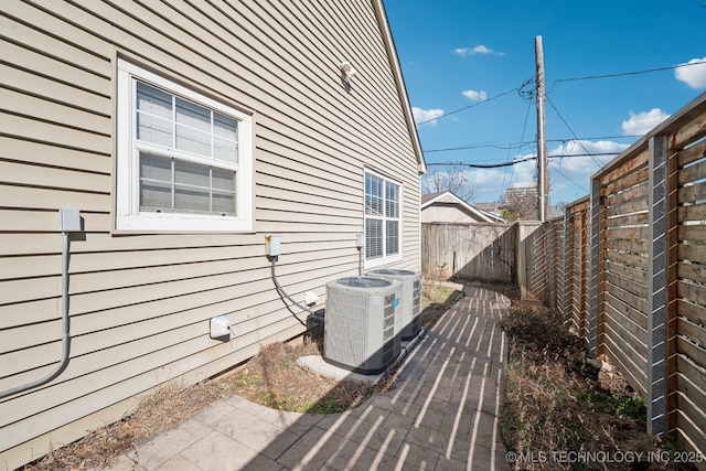 view of side of property featuring a patio area, a fenced backyard, and central air condition unit