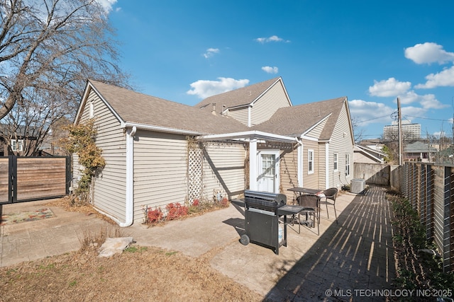 back of property featuring central AC unit, a shingled roof, a patio area, and a fenced backyard