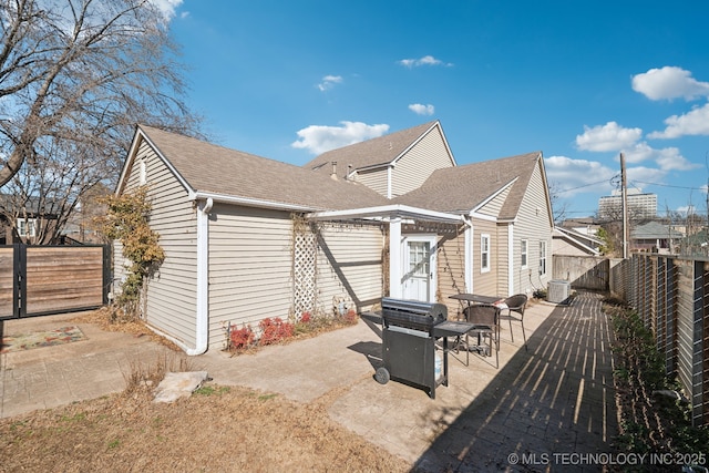 exterior space featuring a patio area, a fenced backyard, a shingled roof, and central AC