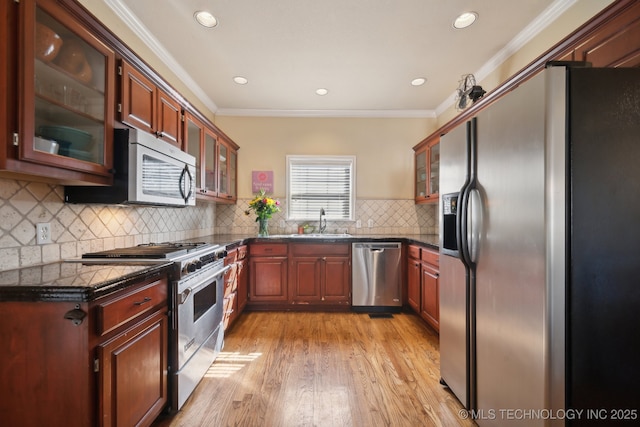 kitchen featuring crown molding, appliances with stainless steel finishes, light wood finished floors, and a sink