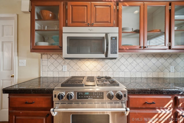 kitchen with tasteful backsplash, glass insert cabinets, and appliances with stainless steel finishes