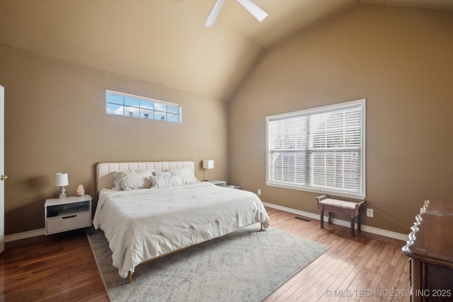 bedroom with visible vents, vaulted ceiling with skylight, baseboards, a ceiling fan, and hardwood / wood-style flooring