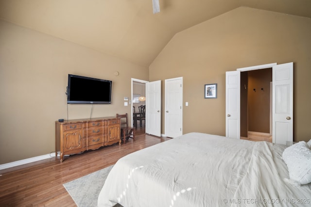 bedroom with wood finished floors, high vaulted ceiling, baseboards, and a ceiling fan