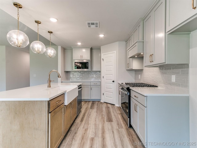 kitchen featuring pendant lighting, light countertops, visible vents, appliances with stainless steel finishes, and wall chimney exhaust hood