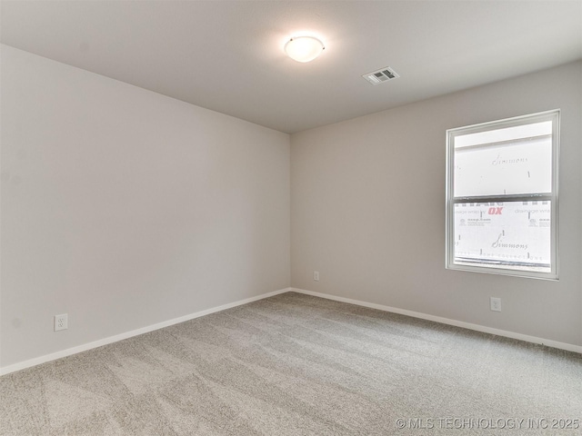 spare room with carpet floors, visible vents, and baseboards