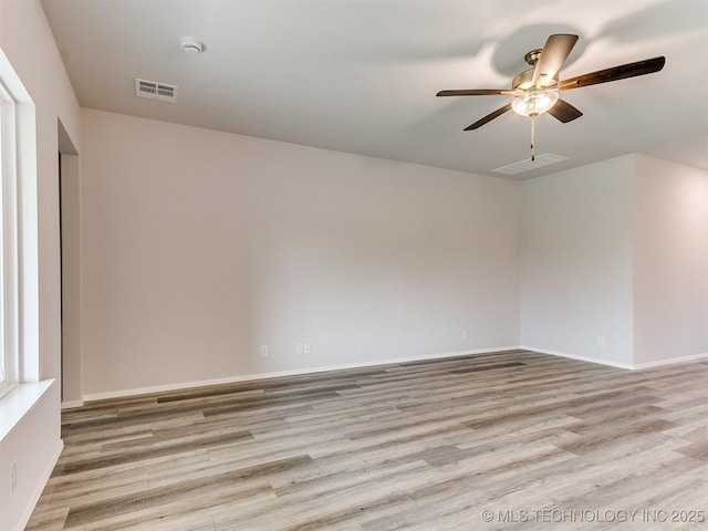 spare room featuring a ceiling fan, visible vents, light wood-style flooring, and baseboards