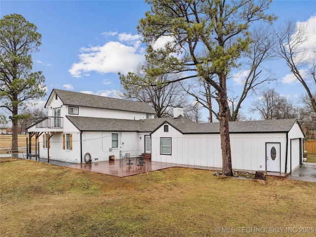 back of house featuring a garage, a yard, roof with shingles, a chimney, and a patio area