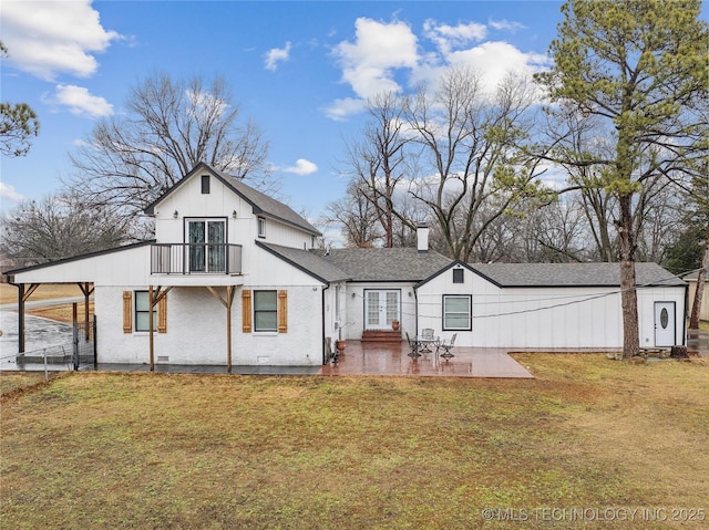 back of property with a yard, brick siding, a patio, and a balcony