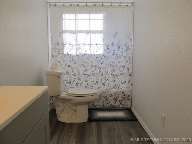 bathroom with toilet, a shower, wood finished floors, and vanity