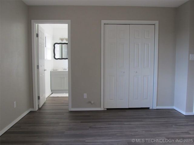 unfurnished bedroom with a closet, dark wood finished floors, and baseboards