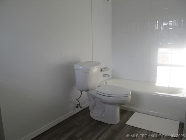 bathroom featuring toilet, baseboards, tub / shower combination, and wood finished floors