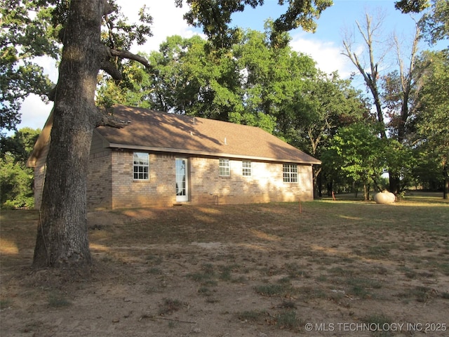 view of property exterior featuring brick siding and a lawn