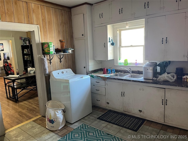 washroom with washer / clothes dryer, cabinet space, a sink, and wood walls