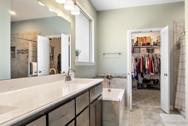 bathroom featuring a spacious closet, tiled shower, vanity, and a bath