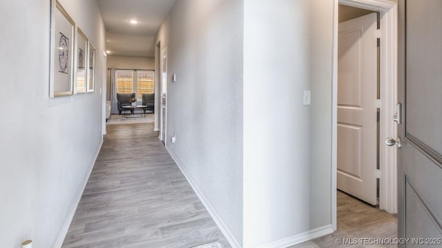 corridor with light wood-style floors and baseboards