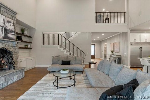 11904 S Toledo Ave, Tulsa, OK 74137 - living area featuring a fireplace, wood finished floors, a towering ceiling, baseboards, and stairs